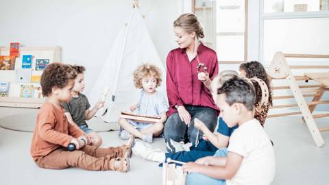 Pedagogisch medewerker van Kindergarden geeft muziekles aan de peuters op de kinderopvang